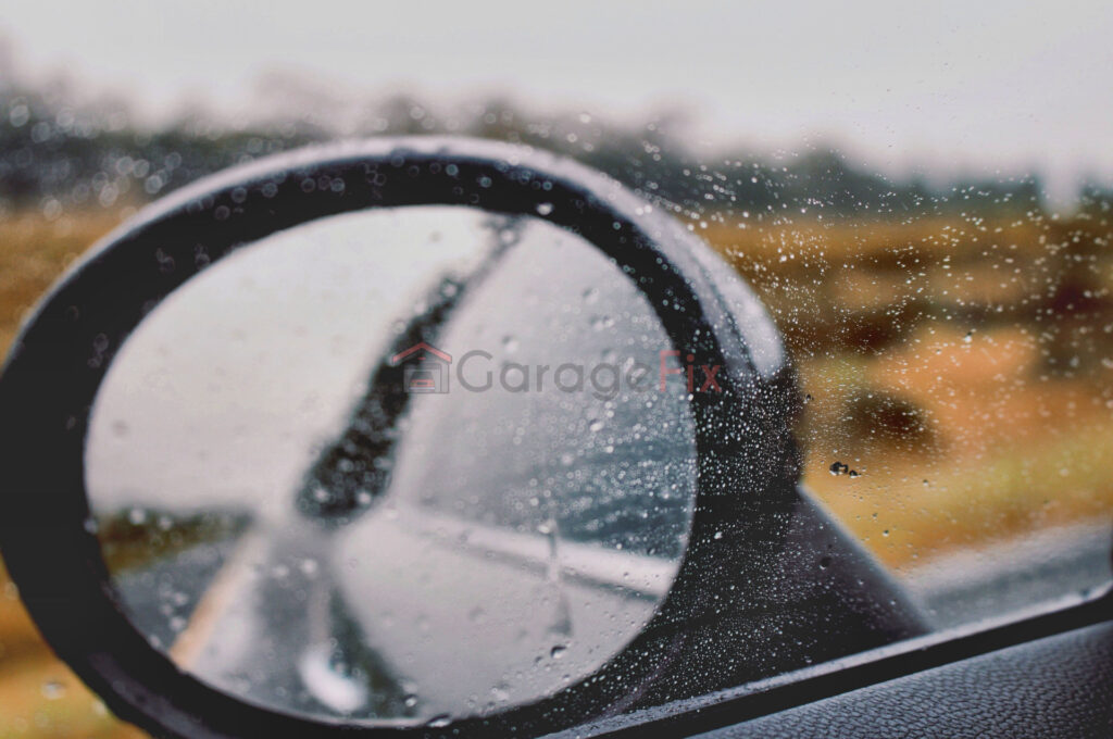 A car rear view mirror with rain drops on it.