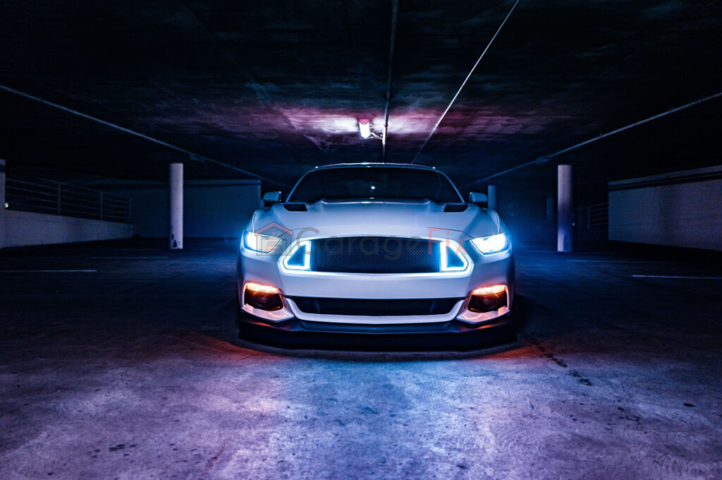 A white ford mustang parked in a garage at night.