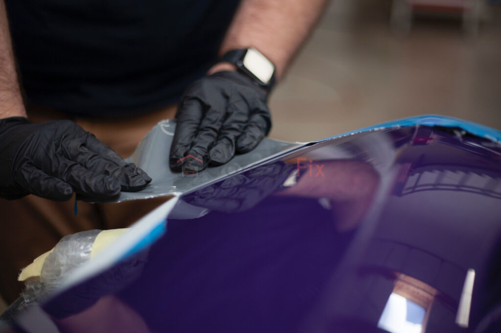 A man in black gloves is working on a purple car.