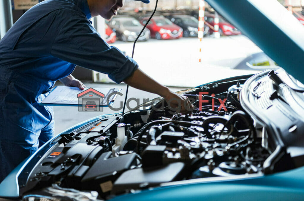 A mechanic working on a blue car in a garage.