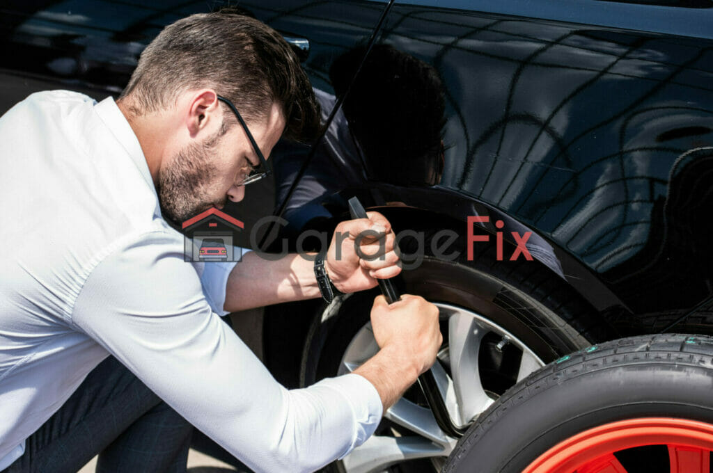 A man fixing a tire on a black car.