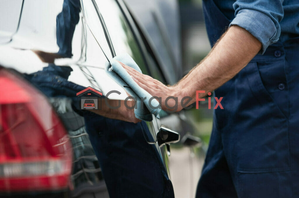 A man cleaning a car with a cloth.