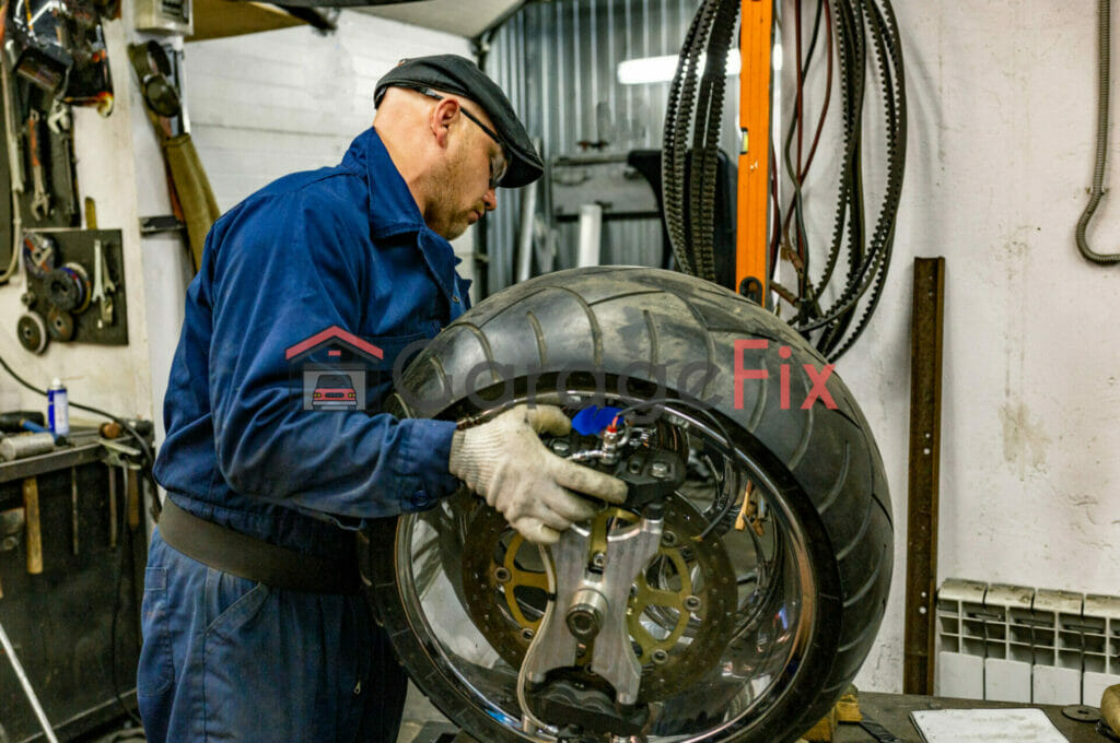 A man working on a motorcycle tire in a garage.