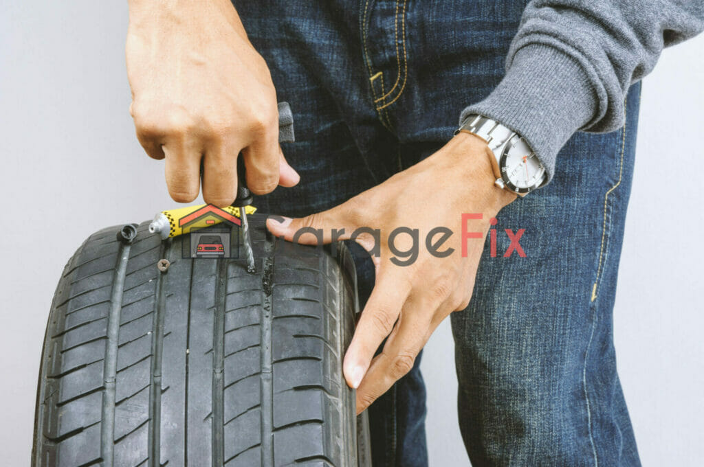 A man fixing a tire on a white background.